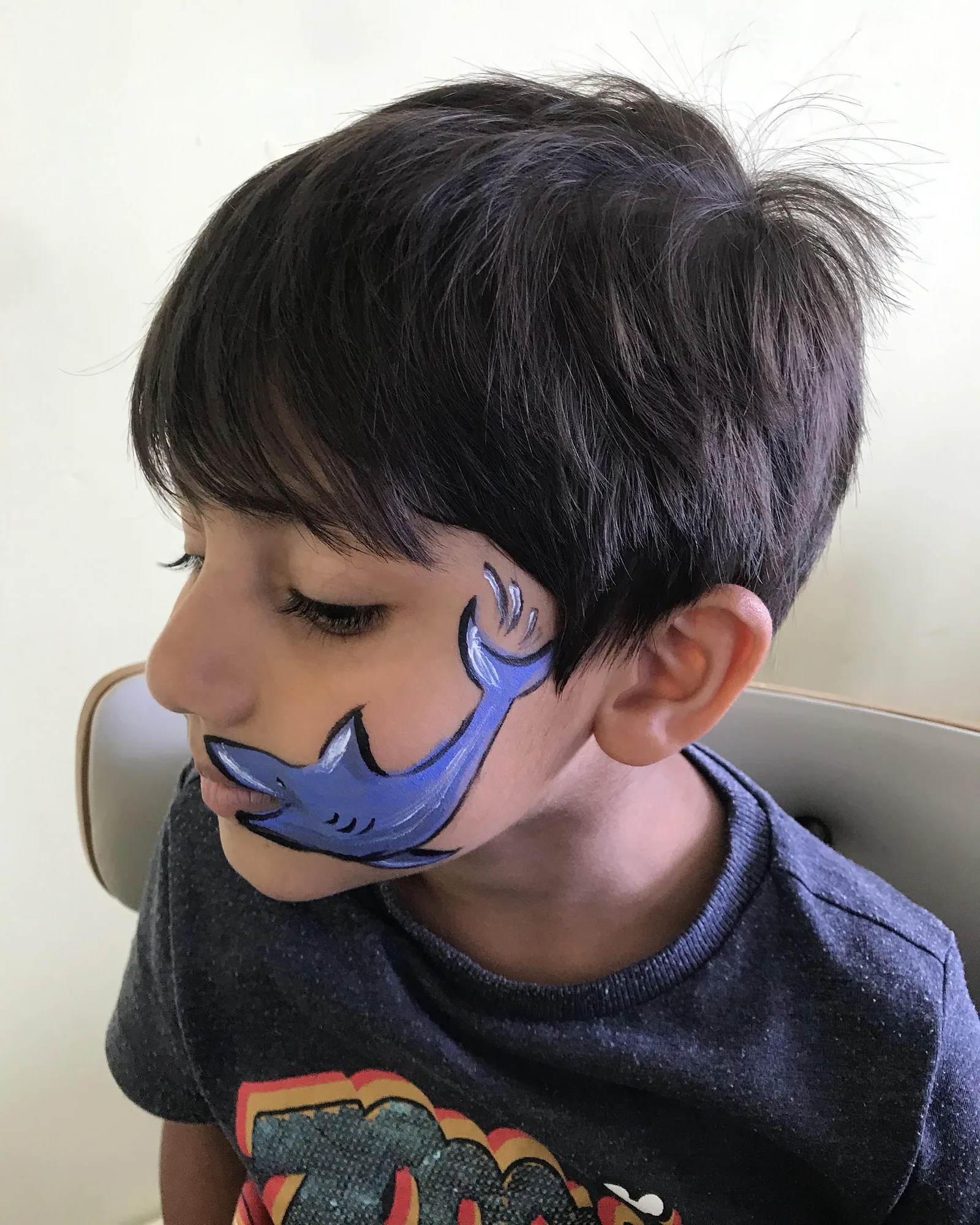 Piya's shark face-painting design on a child, side profile