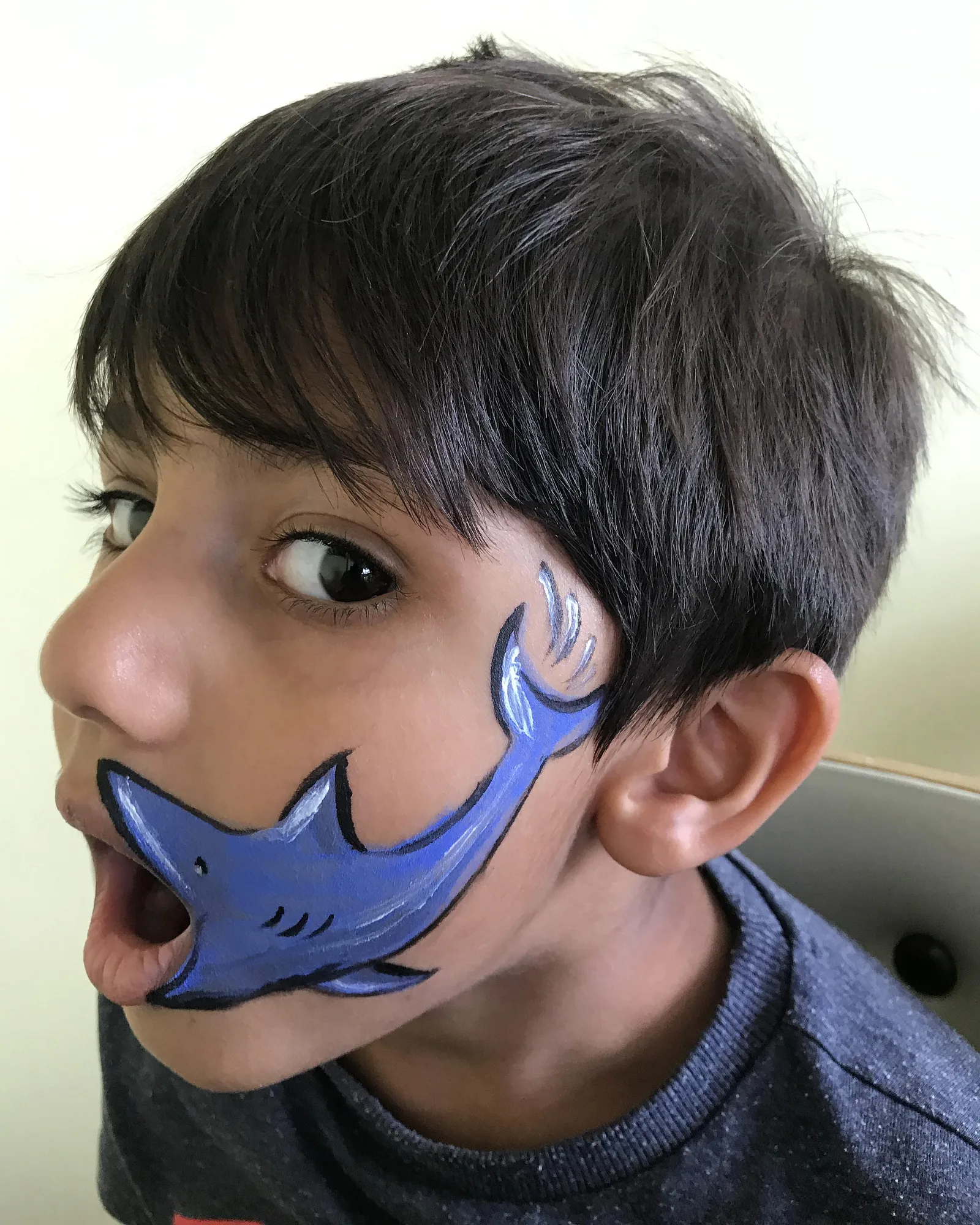 Piya's shark face-painting design on a child, jaw open
